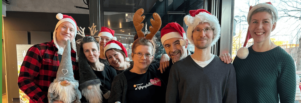 Suomen Kylien tiimi järjestäytyneenä joulukuvaan tonttulakit ja poronsarvet päissään Tampereella vuonna 2024.